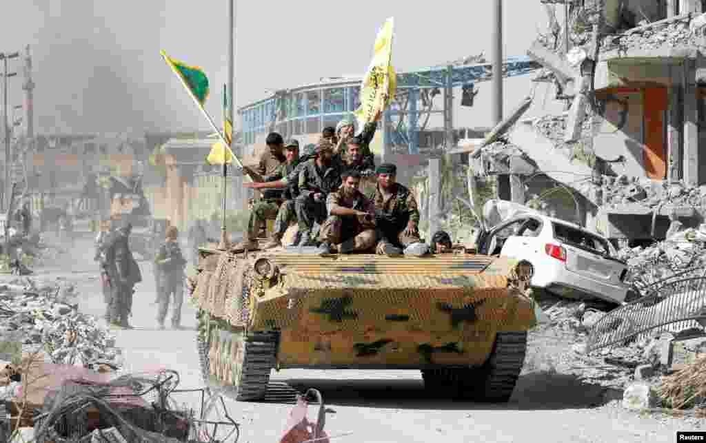 Syrian Democratic Forces (SDF) fighters ride atop a military vehicle in Raqqa as they celebrate victory and the liberation of Raqqa from Islamic State militants.