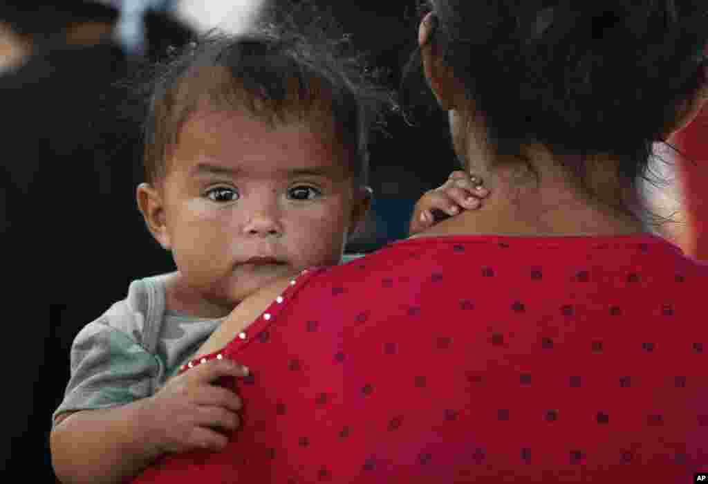A Honduran migrant mother and her 7-month-old child stand in line to board a bus that will take them and other migrants to Monterrey, from an immigration center in Nuevo Laredo, Mexico, July 18, 2019.