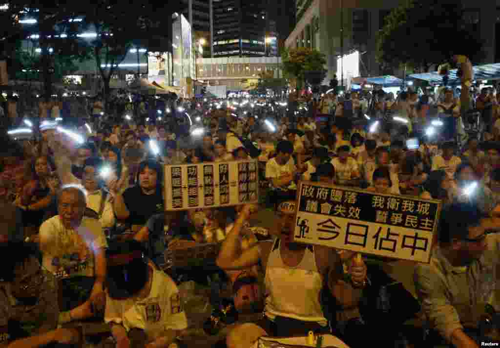 Protesters sing while waving mobile phones during an overnight sit-in, financial district of Hong Kong, July 1, 2014.