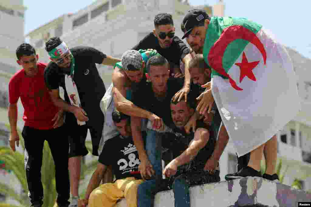 Demonstrators spray water on a man who tried to self-immolate himself during a protest demanding the removal of Algeria's ruling elite, in Algiers.