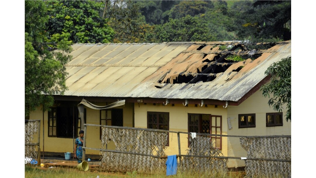 FILE - A woman stands outside a damaged school dormitory after it was set on fire in Bafut, in the northwest English-speaking region of Cameroon, Nov. 15, 2017.