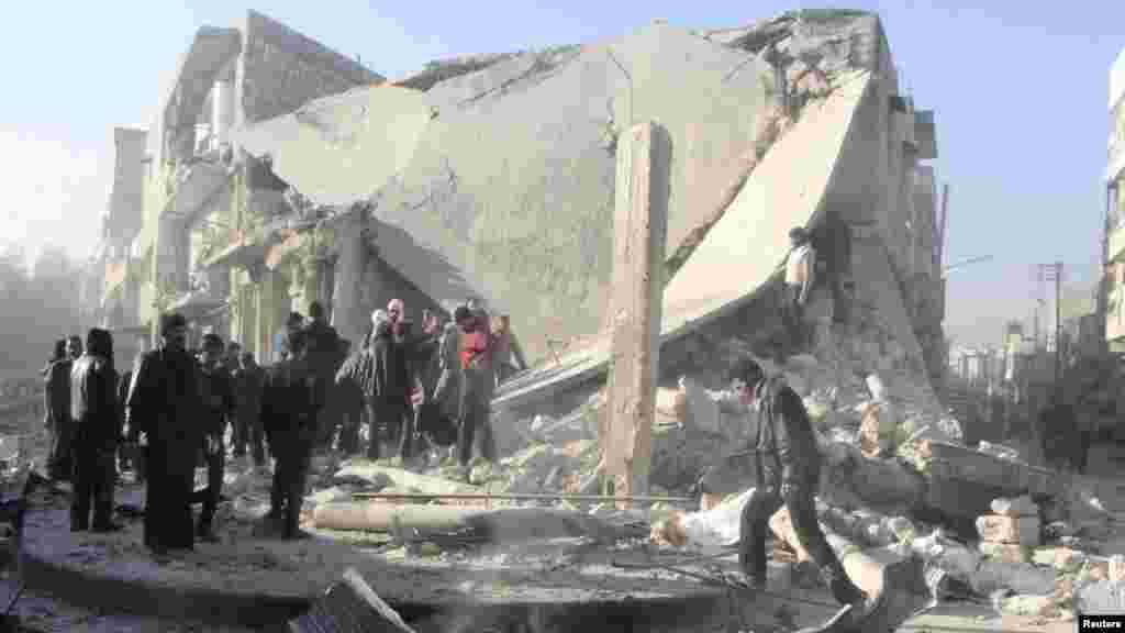 People inspect a site damaged by what activists said was an air raid by forces loyal to Syrian President Bashar Al-Assad in the al-Marja district of Aleppo, Dec. 23, 2013. 
