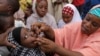 FILE - Health official administers a polio vaccine to a child in Kawo Kano, Nigeria. 