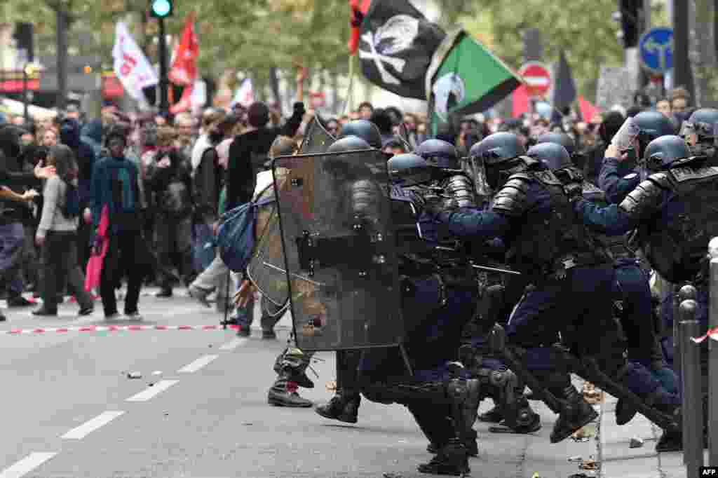 Anti-riot police charge protesters on the sidelines of a demonstration in Paris, part of a nationwide strikes and demonstrations day called by nine unions representing 5,4 million public sector workers to show their "profound disagreement" with French president's bid to transform the gargantuan public service and government's plans to freeze their pay and eliminate 120,000 public jobs.