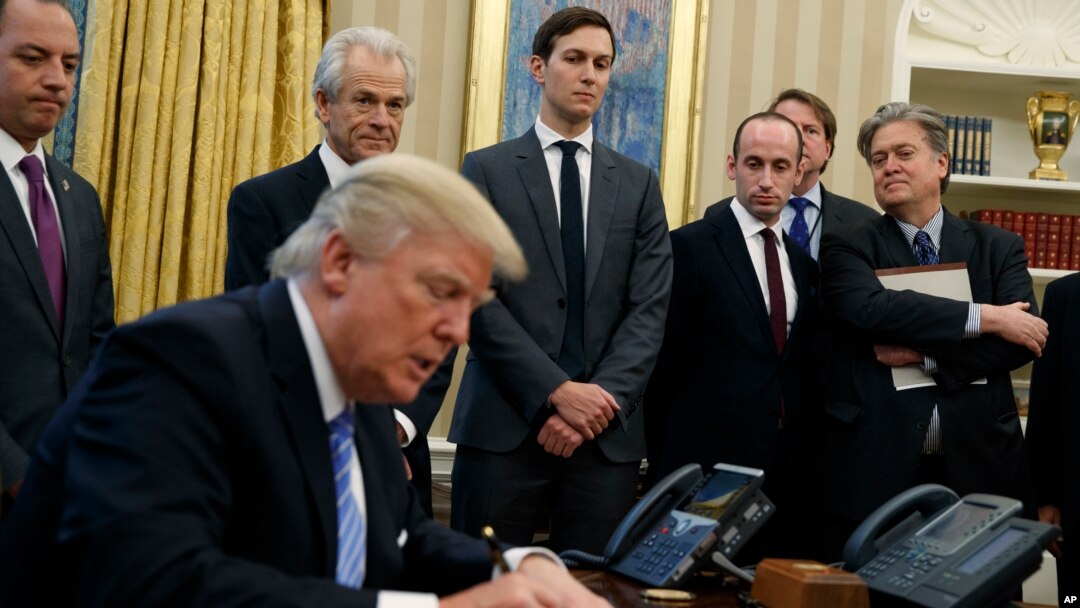 President Donald Trump signs an executive order in the Oval Office of the White House, Monday, Jan. 23, 2017, in Washington. 