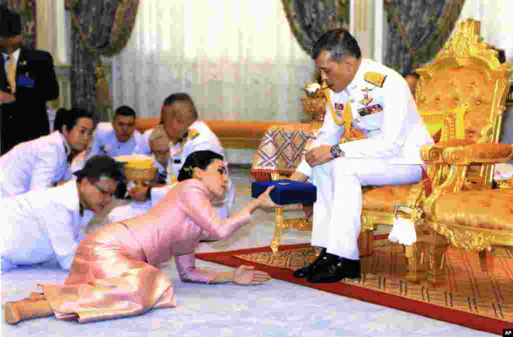 In this photo released by Bureau of the Royal Household ,Thailand's King Maha Vajiralongkorn Bodindradebayavarangkun, right, presents a gift to Queen Suthida Vajiralongkorn Na Ayudhya at Ampornsan Throne Hall in Bangkok. An announcement in the Royal Gazette said Suthida Vajiralongkorn Na Ayudhya is legally married to the 66-year-old king, and is now Queen Suthida.