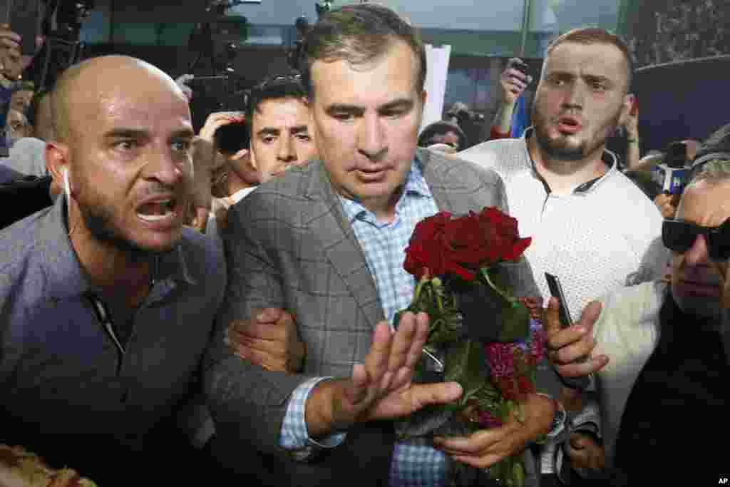 Georgia's ex-President Mikheil Saakashvili, center, surrounded by bodyguards, leaves a terminal upon his arrival at Boryspil Airport, outside Kiev, Ukraine. Saakashvili has been given his Ukrainian citizenship back by the country's new president.