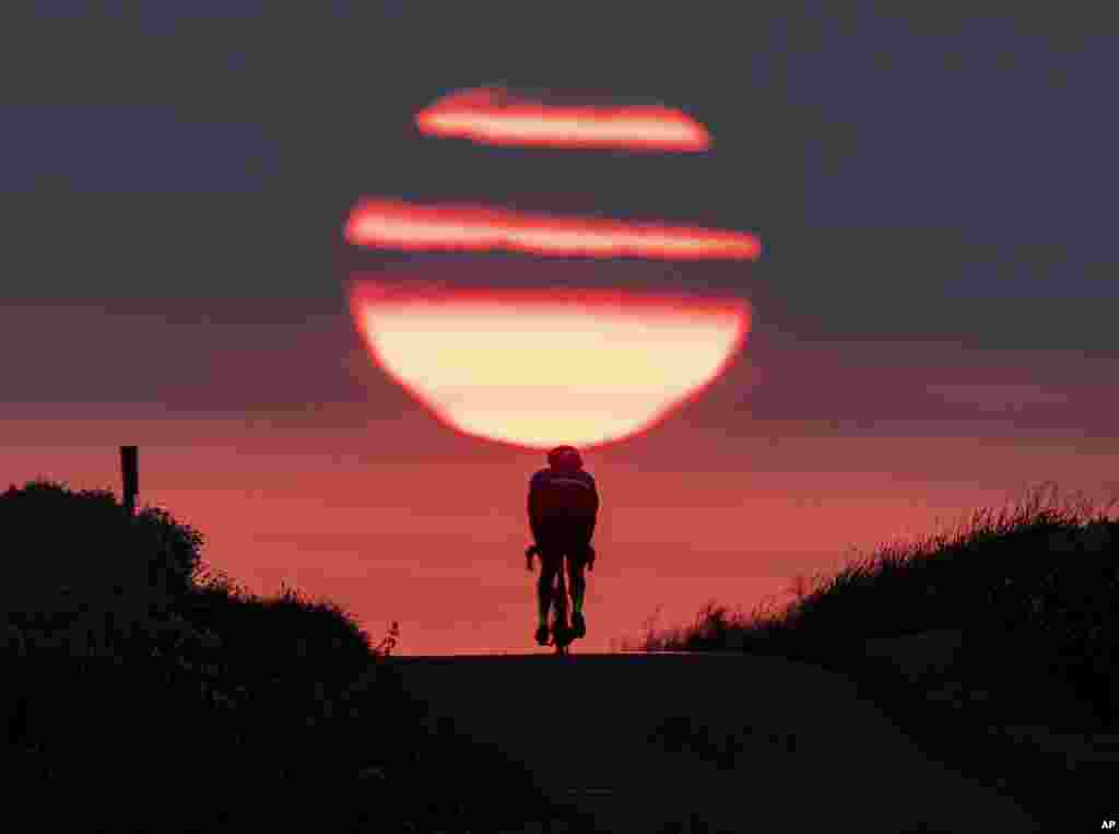 A man rides his bike on a small path as the sun rises in Frankfurt, Germany, June 27, 2019.