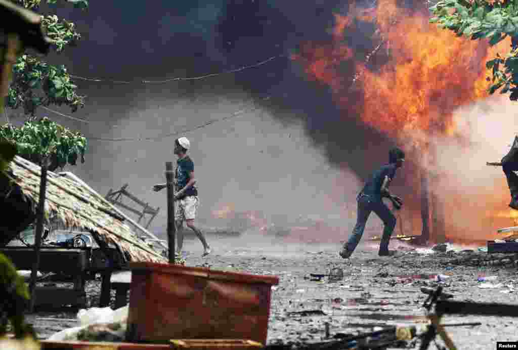 Những người đàn ông Rohingya đứng giữa những ngôi nhà bị đốt cháy tại Sittwe, 10/6/2012.