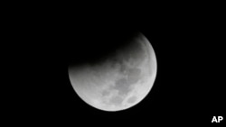 FILE - Earth starts to cast its shadow on the moon during a complete lunar eclipse seen from Jakarta, Indonesia, Aug. 28, 2018.