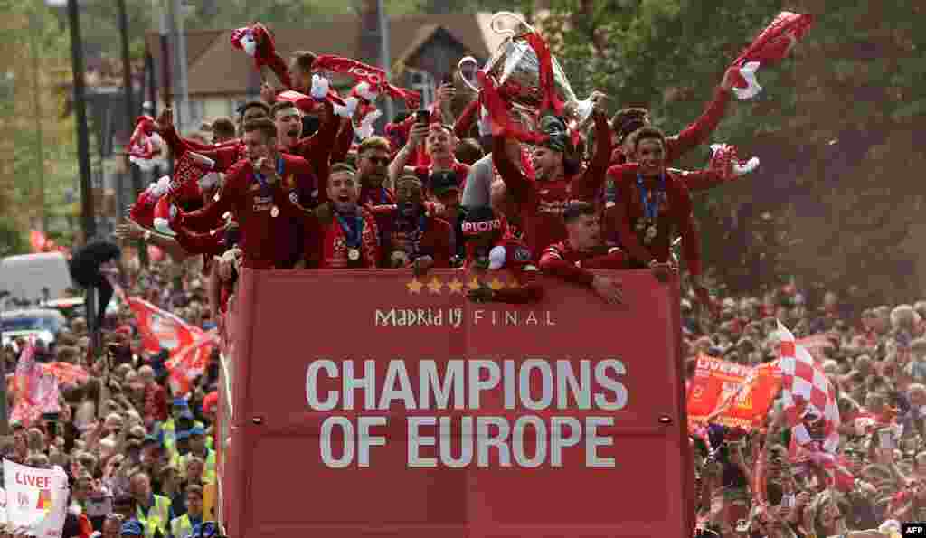 Liverpool's Spanish defender Alberto Moreno (3R) holds aloft the European Champion Clubs' Cup trophy as he stand with teammates during an open-top bus parade around Liverpool, north-west England, after winning the UEFA Champions League final football match between Liverpool and Tottenham.