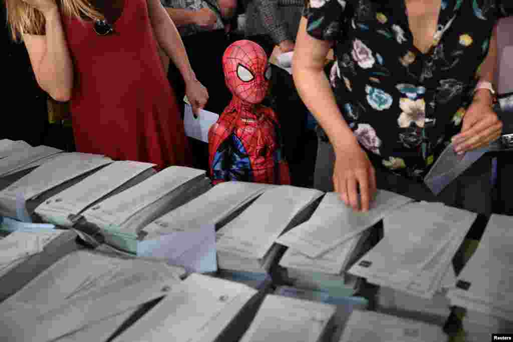 A kid in a Spiderman costume stands next to a ballot table for the European Parliament election at a polling station in Madrid, Spain.