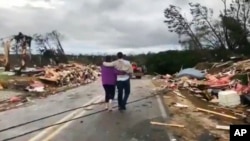 Residentes del condado de Lee en Alabama, sur de EE.UU., caminan entre los escombros dejados por un tornado el domingo, 3 de marzo de 2019.
