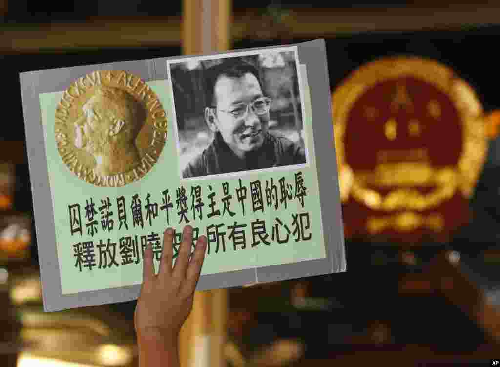 2010年10月8日,正在監牢服刑的“零八憲章”起草人,中國民主運動人士劉曉波獲得諾貝爾和平獎的消息傳來,香港民主活動人士前往中國駐香港聯絡辦公室大樓前示威,敦促中國政府釋放劉曉波,人們舉著劉曉波及諾貝爾獎牌的照片。
