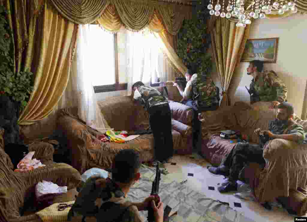 A Free Syrian Army fighter fires his sniper rifle from a house in Aleppo, August 14, 2012.