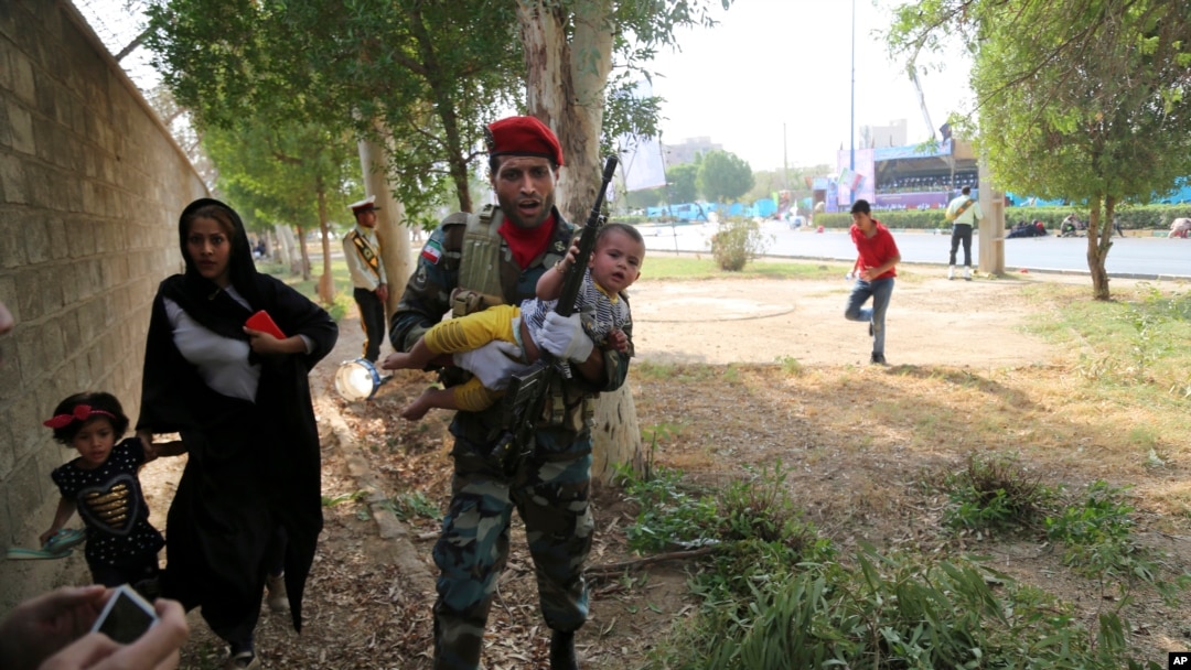 In this photo provided by Mehr News Agency, an Iranian army member carries a child from a shooting scene during a military parade marking the 38th anniversary of Iraq's 1980 invasion of Iran, in the southwestern city of Ahvaz, Iran, Sept. 22, 2018.