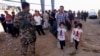 A Kurdish policeman stands guard while refugees from Mosul head to the self-ruled northern Kurdish region in Irbil, Iraq, 350 kilometers (217 miles) north of Baghdad, June 10, 2014.