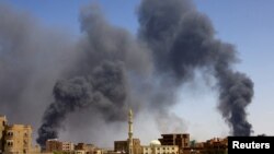 Homem caminha enquanto se levanta fumo sobre os edifícios após bombardeamento aéreo em Cartum Norte. Fotografia de arquivo