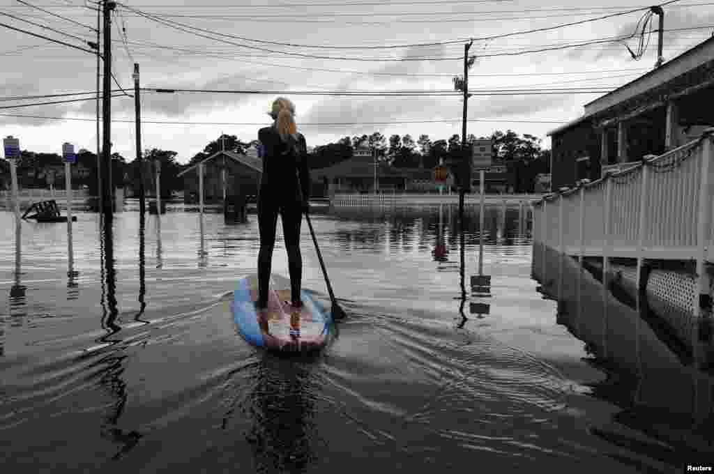 Zoe Jurusik paddleboards down a flooded city street after Hurricane Sandy in Bethany Beach, Delaware, Oct. 30, 2012.