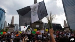 Una persona sostiene una bandera negra de "duelo" y flores durante una protesta por el asesinato del fotoperiodista Rubén Espinosa en el monumento Ángel de la Independencia de Ciudad de México, el 2 de agosto de 2015. 