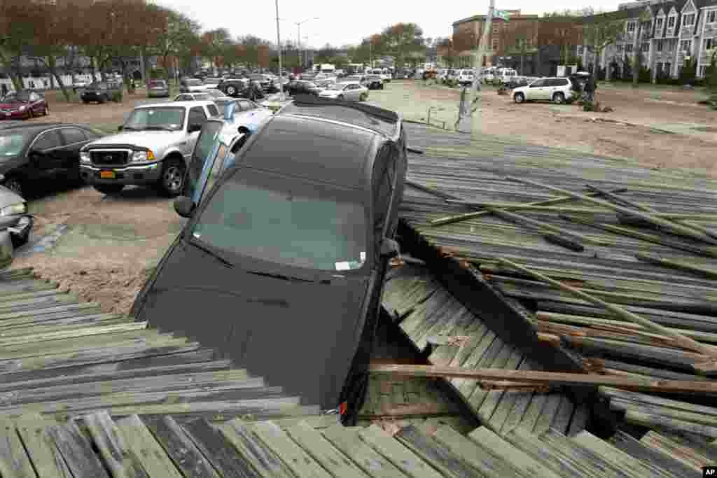 Pedestrians walk past the boardwalk and cars displaced by Superstorm Sandy, near Rockaway Beach, Queens, New York, Oct. 30, 2012.