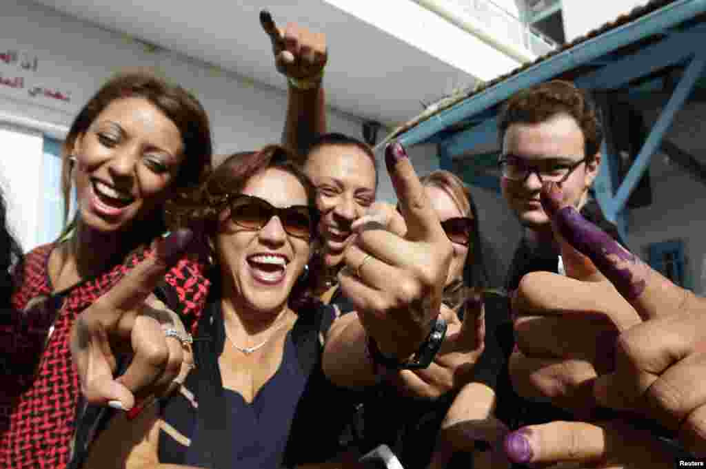 Tunisians show their ink-stained fingers after casting their votes, in Tunis, Tunisia, Oct. 26, 2014.