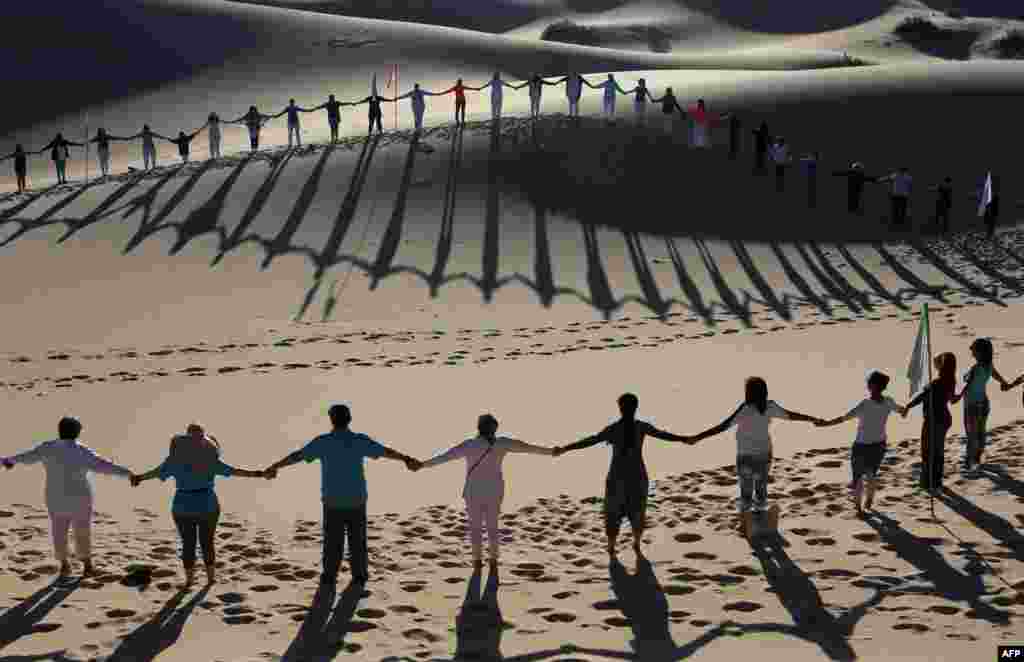 People attend a yoga class during a meeting organized by the YSYoga System community in the Samalayuca Dune Fields in the municipality of Juarez, Chihuahua State, Mexico, May 25, 2019.
