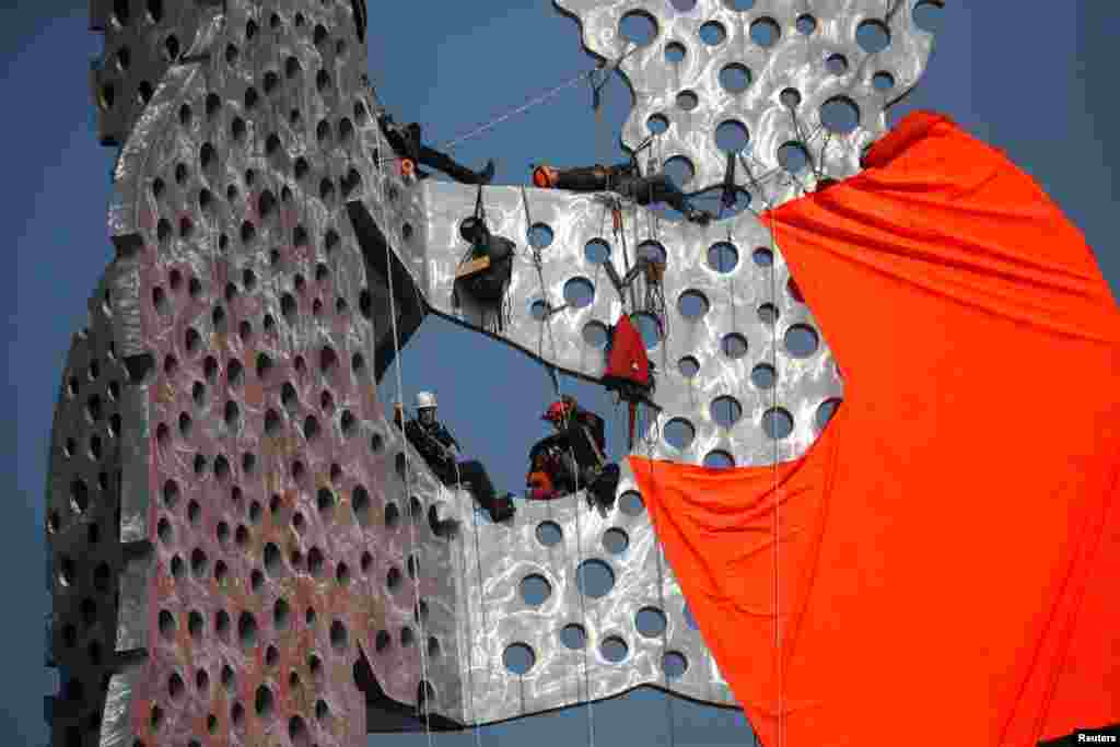 Activists supporting the sea rescue of migrants in the Mediterranean Sea attach a giant life vest to the "Molecule Man" sculpture in Berlin, Germany.