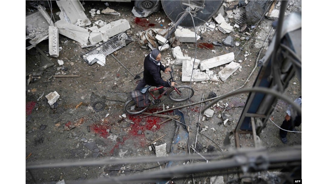 A Syrian man walks with a bicycle amid the rubble of destroyed buildings following a reported air strike by Syrian government forces in the rebel-held area of Douma, east of the capital Damascus, on Oct. 29, 2015.