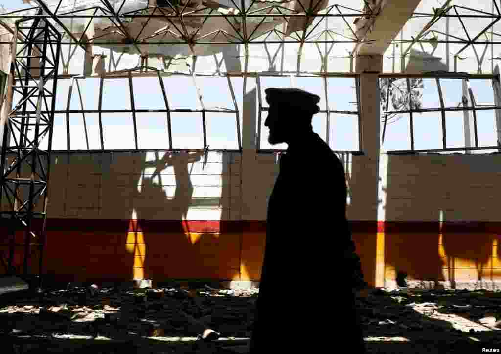 An Afghan man inspects the broken glass from his garage at the site of a suicide attack in Kabul, Afghanistan.