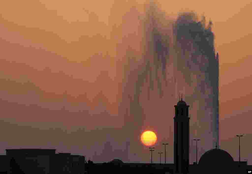 The sun sets behind a mosque and the landmark Jiddah fountain, in Jiddah, Saudi Arabia, Aug. 29, 2019.