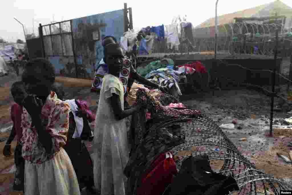 South Sudanese girls collect their laundry from a barbed wire in a camp for displaced persons in the UNMISS compound in Tongping, Juba, South Sudan, Feb. 19, 2014. 