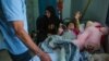 Sara, 8, cries as her father looks at her one broken leg — the other has been severed — in Qamishli, Syria, Oct. 15, 2019. (Y. Boechat/VOA)