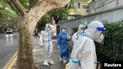 FILE PHOTO: Workers in protective suits walk on a street, following the coronavirus disease (COVID-19) outbreak, in Shanghai