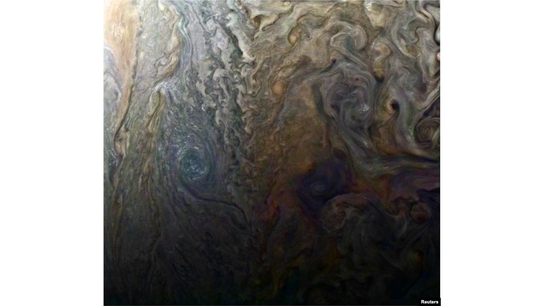 FILE - NASA's enhanced-color image of a mysterious dark spot on Jupiter shows a Jovian "galaxy" of swirling storms in this image captured by NASA's Juno spacecraft, Feb. 2, 2017, at an altitude of 9,000 miles (14,500 kilometers) above Jupiter's cloud tops.