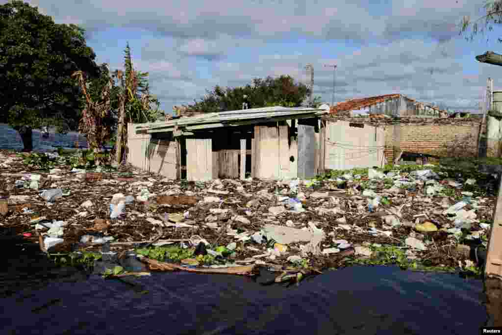Houses are pictured partially submerged beside debris in a flooded street after heavy rains caused Paraguay River to overflow, in a neighborhood on the outskirts of Asuncion, Paraguay, May 13, 2019.