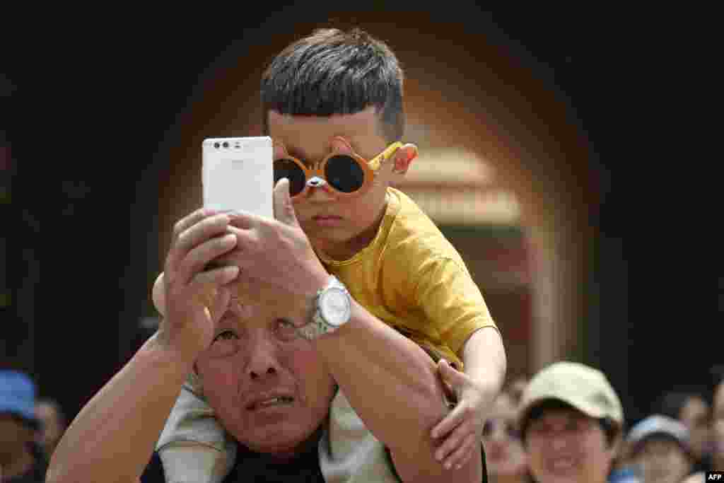 A man takes a selfie with a young boy after a visit to the Forbidden City, the former home of China's emperors, during a four-day national holiday marking May Day, in Beijing.