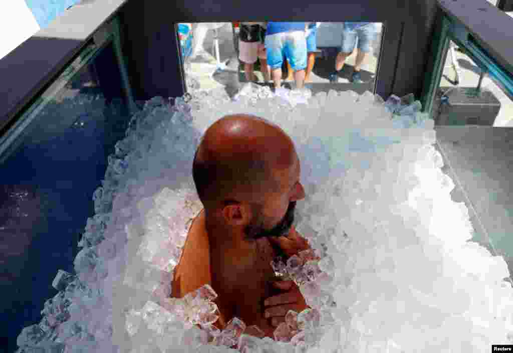 Austrian sportsman Josef Koeberl stands still in an ice-filled glass cabin as he tries to set a World Record of staying in ice in Vienna, August 10, 2019.
