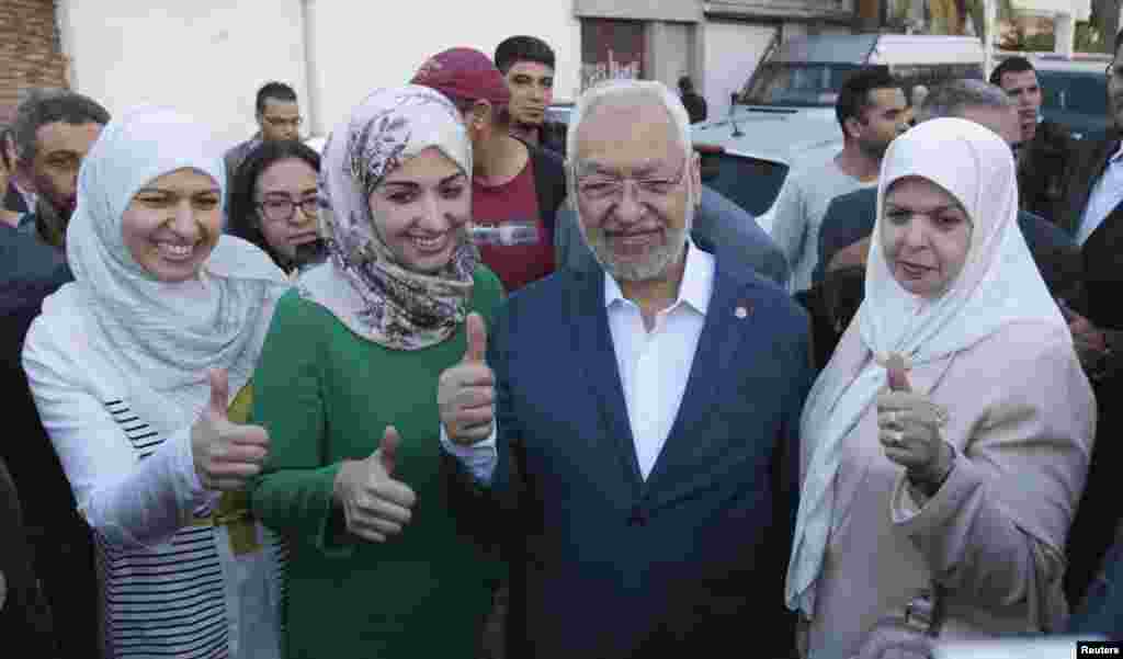 Rached Ghannouchi, leader of the Tunisian Islamist party Ennahda, gestures with his wife and two daughters Yousra (left) and Soumaya (2nd left) at a polling station in Tunisia, Oct. 26, 2014.