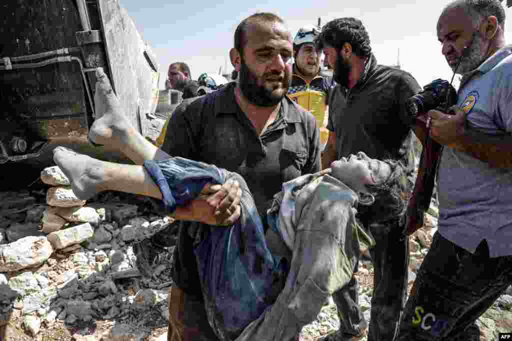 A Syrian carries the body of a child at the site of a reported regime airstrike on the village of Deir Sharqi on the eastern outskirts of Maaret al-Numan in Syria's northern province of Idlib, Aug. 17, 2019.