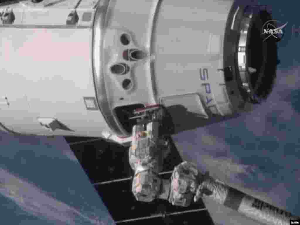In this video frame grab provided by NASA, the International Space Station's robotic arm, lower right, operated by station commander Butch Wilmore, reaches for the SpaceX Dragon spacecraft as it soars more than 420km above the Mediterranean Sea on Monday, Jan. 12, 2015.