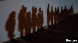 La frontera sur ha experimentado este año insólitos aumentos de migrantes que solicitan asilo como este grupo que proyecta sombra en una pared mientras forman una cola para ser procesadas por la Patrulla Fronteriza de EE. UU. después de entrar de forma irregular al territorio.