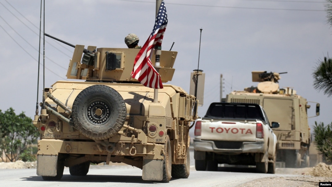 FILE - The U.S. flag flutters on a military vehicle in Manbij, Syria, May 12, 2018.