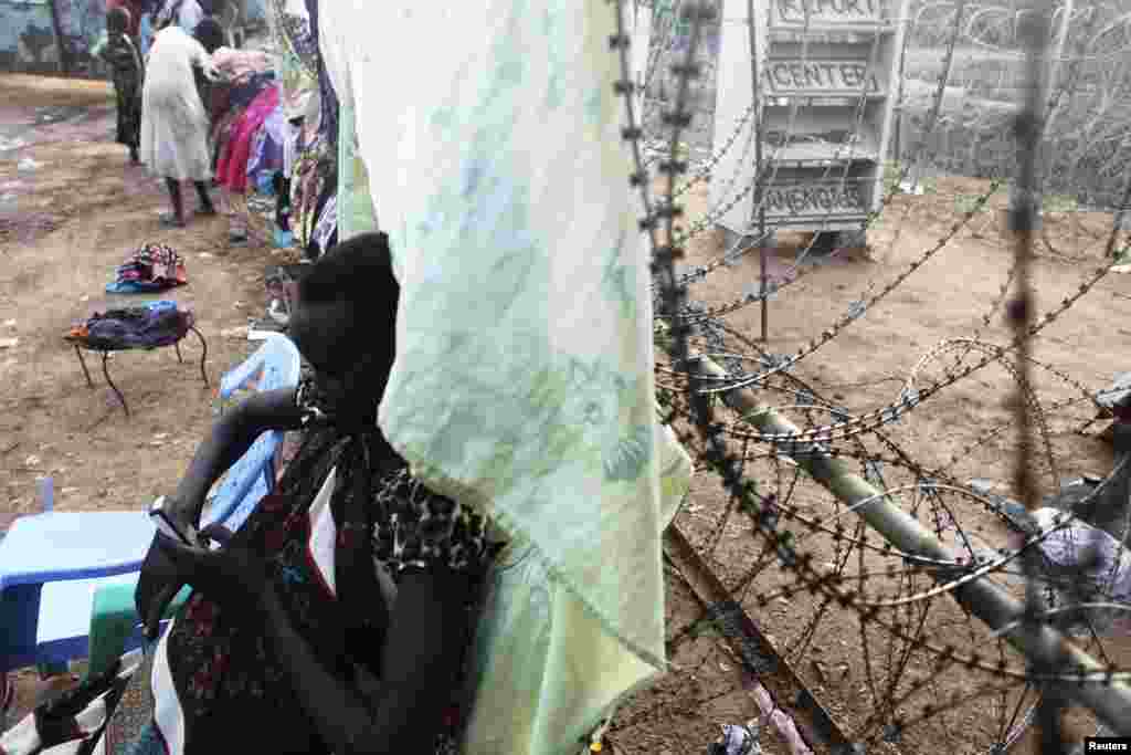 A South Sudanese woman uses her phone as she leans against a barbed wire in a camp for displaced persons in the UNMISS compound in Tongping, Juba, South Sudan, Feb. 19, 2014. 
