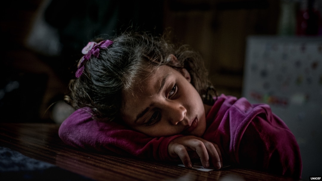 FILE - Mariem, 8, a refugee from Syria, rests in her family’s shelter at a refugee camp in Greece, March 14, 2017. 