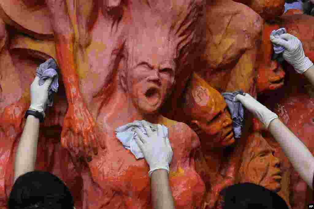 University students clean the 'Pillar of Shame' statue, a memorial for those killed in China's 1989 Tiananmen crackdown, at the University of Hong Kong, June 4, 2019.