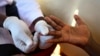 FILE - A doctor draws blood from a man to check for HIV/AIDS at a mobile testing unit in Ndeeba, a suburb in Uganda's capital Kampala. 