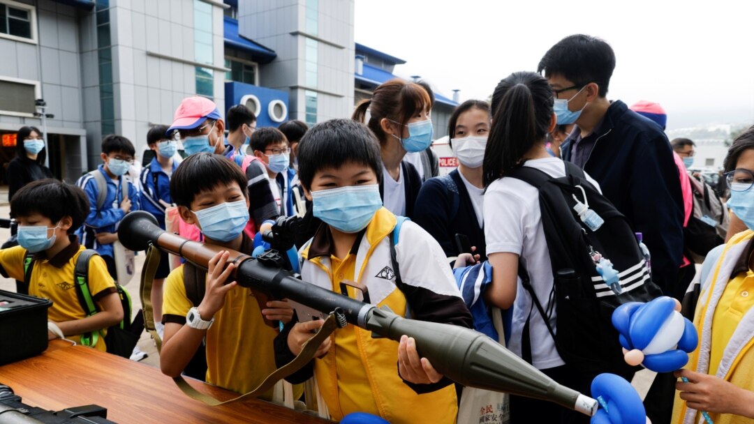 香港小學生在2021年4月15日的“全民國家安全教育日”展覽上拿起仿造的榴彈發射器 (路透社照片)
