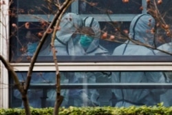 Members of the World Health Organization team, tasked with investigating the origins of COVID-19, don personal protection suits during a visit at the Hubei Animal Epidemic Disease Prevention and Control Center in Wuhan, China on Feb. 2, 2021. REUTERS/Thomas Peter
