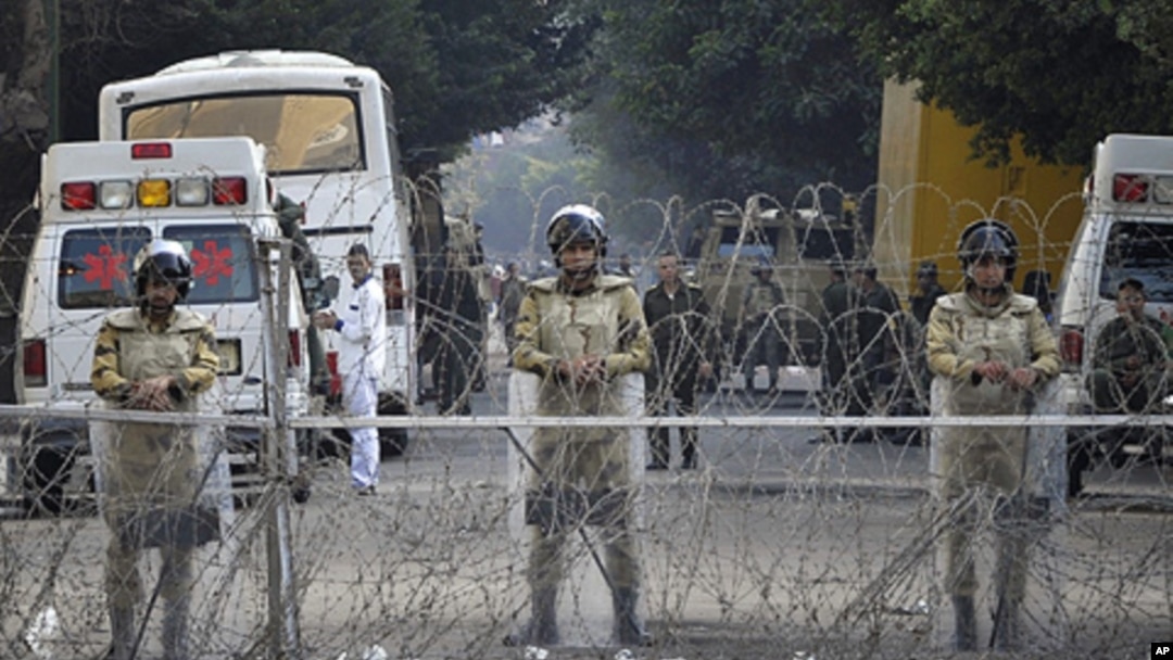Egyptian soldiers stand behind a barbed wire fence while guarding the Cabinet building near Tahrir Square in Cairo, Egypt, Saturday, Nov. 26, 2011.